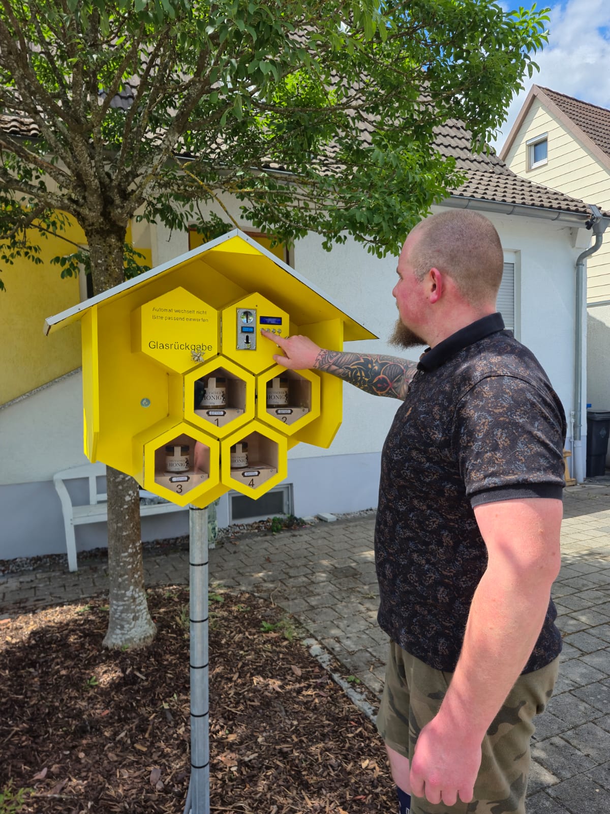 Person öffnet ein Fach des gelben Honigautomaten
